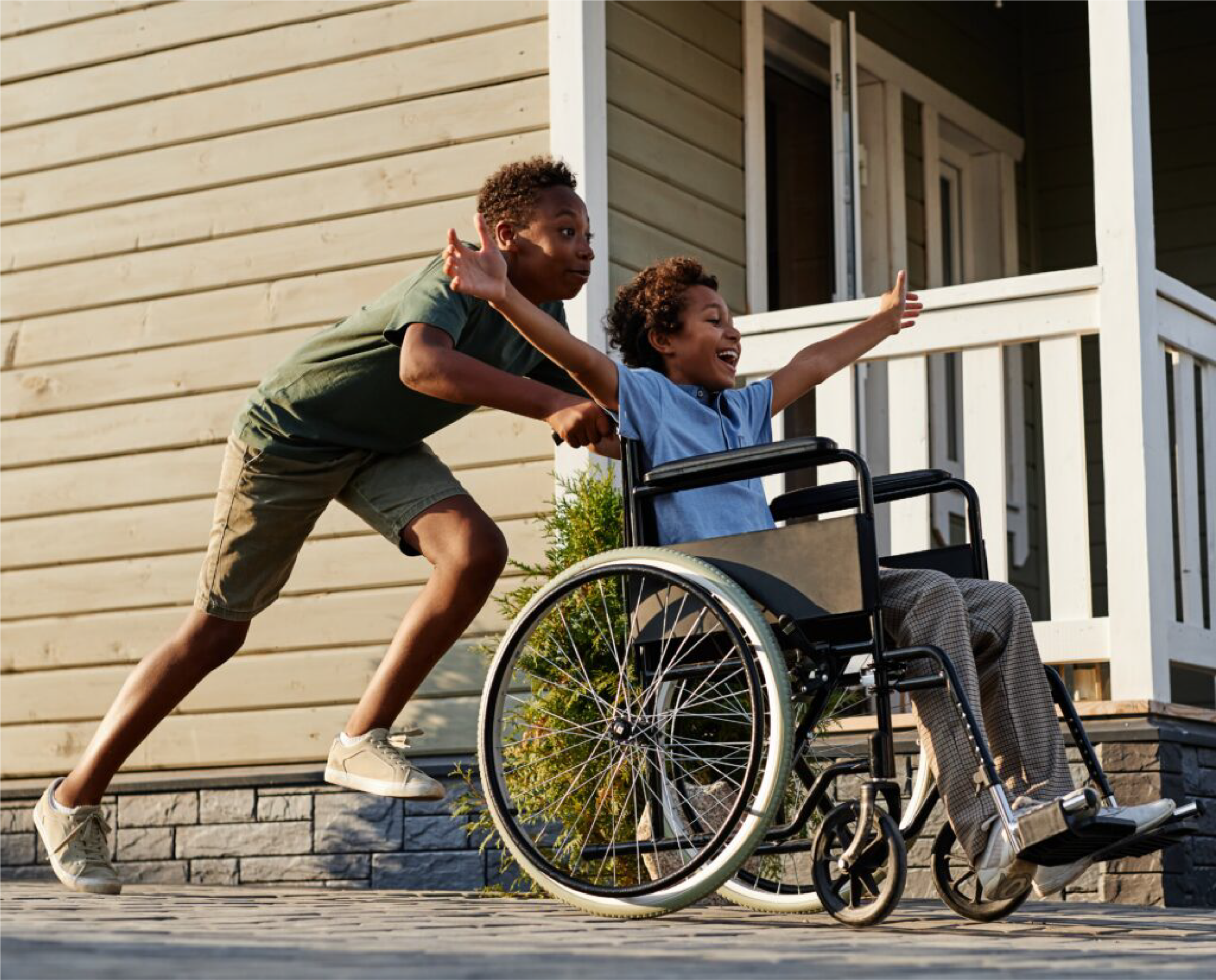 Two young people heading out along the street together, one pushing the other's wheelchair