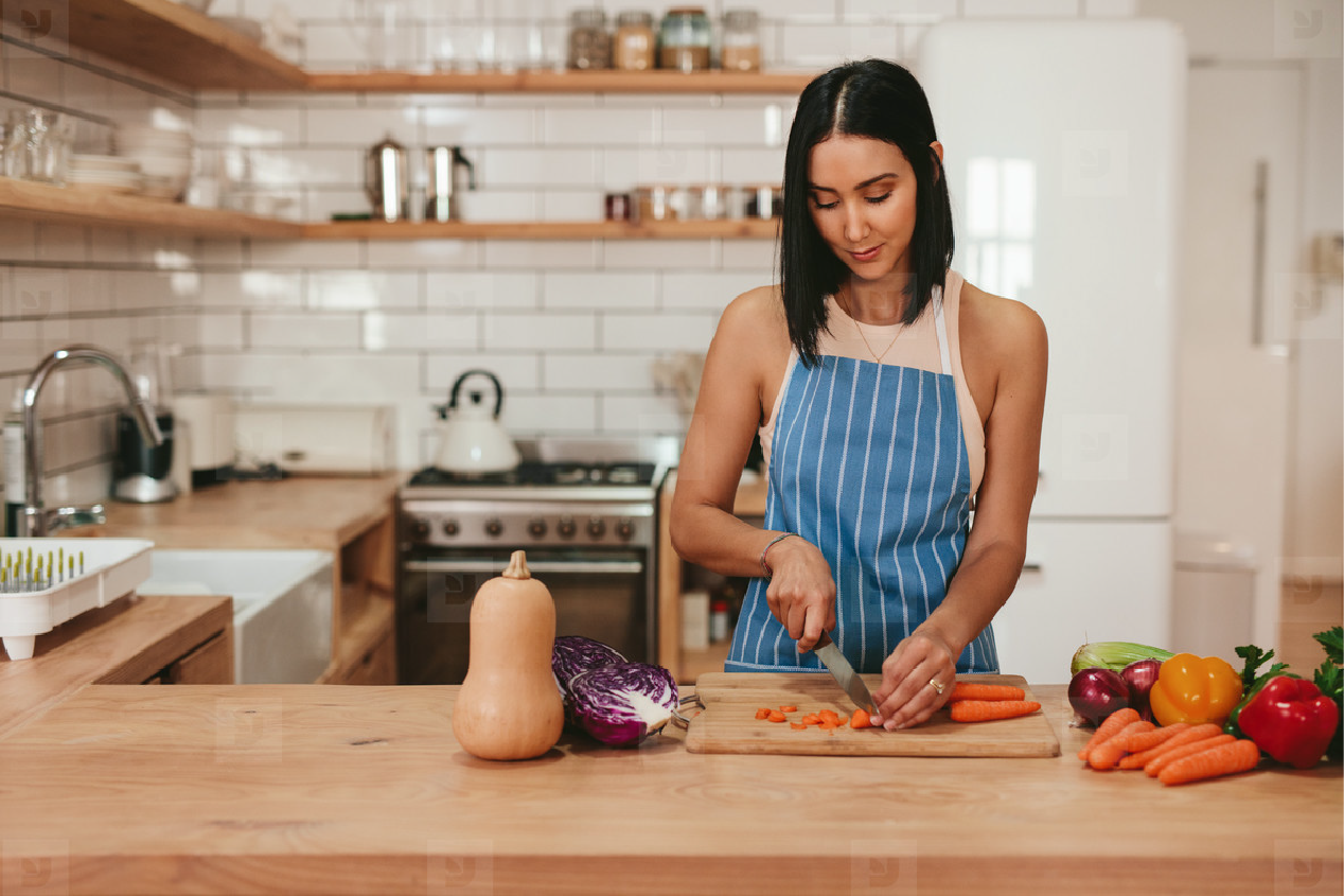 Young adult chopping vegetables at the kitchen counter